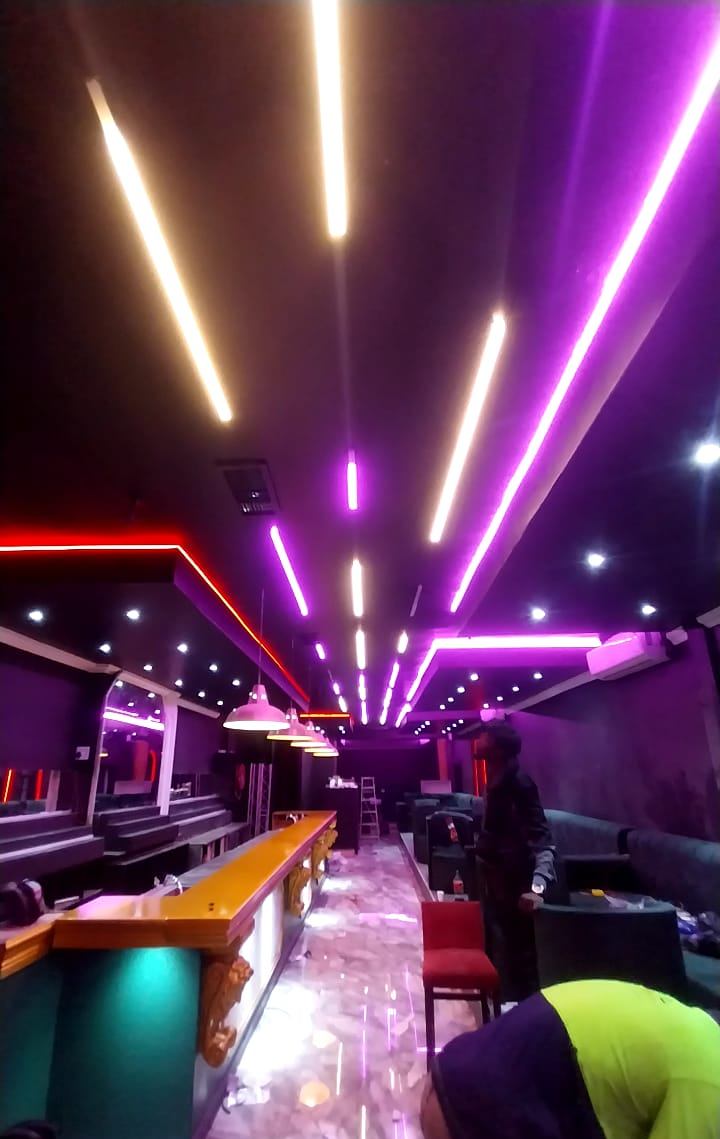 Bar fit-out mid-installation with linear LED profiles in white and purple and red LED ceiling edges
